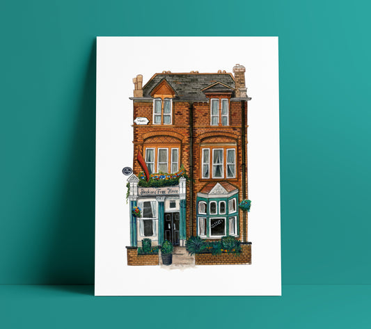 Skehans Pub art print in black frame on wooden floor against white wall